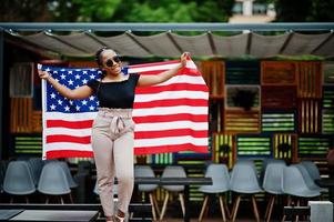 Stylish african american woman in sunglasses posed outdoor with usa flag. photo