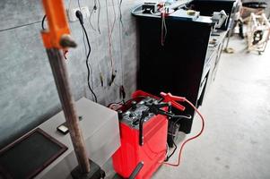Car repair and maintenance theme. Car battery, electric vehicle battery charger via jumper cable. photo