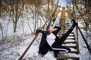 Fashionable long legs brunette model in long black cloak posed outdoor at winter day. photo