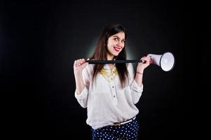 Portrait of a young woman in blue trousers and white blouse posing with megaphone in the studio. photo