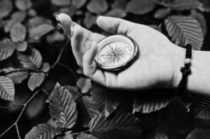 Close-up photo of female hands with compass next to a tree branch.