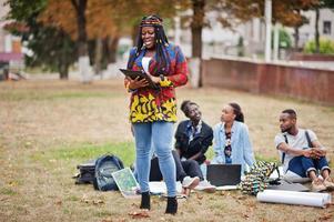 Group of five african college students spending time together on campus at university yard. Black afro friends studying. Education theme. photo