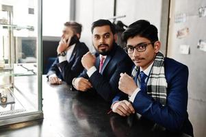 Group of three indian businessman in suits sitting on cafe. photo