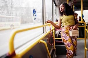 joven mujer afroamericana con estilo montando en un autobús. foto