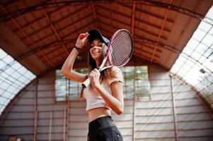 Young sporty girl player with tennis racket on tennis court. photo