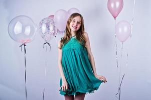 Happy girl in green turqoise dress with colored balloons isolated on white. Celebrating birthday theme. photo