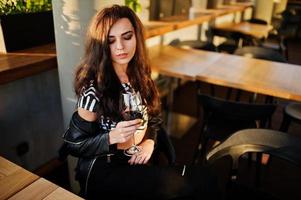 Young curly woman enjoying  her wine in a bar. photo