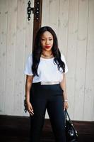 Stylish african american business woman with handbag on streets of city. photo