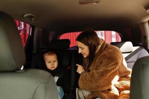 Young mother and child in car. Baby seat on chair. Safety driving concept. photo