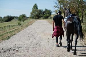 Arab tall beard man wear in black helmet with arabian horse. photo