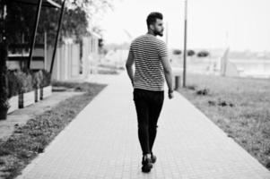 Handsome tall arabian beard man model at stripped shirt posed outdoor. Fashionable arab guy. photo