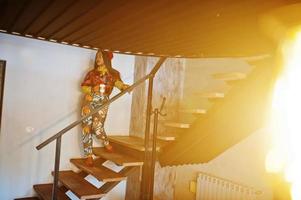 Enthusiastic african american woman in trendy coloured outfit with red beret chilling in cozy cafe, standing on stairs with cup of hot drink in hands. photo