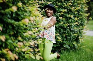 increíble mujer modelo afroamericana en pantalones verdes y sombrero negro posó en el parque. foto