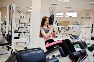 Young brunette sexy slim girl doing workout at gym. photo