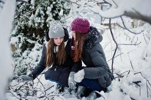 Two funny girls friends having fun at winter snowy day near snow covered trees. photo