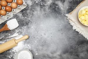 dough preparation recipe bread. equipment accessories baking ingredients bakery cooking. Egg whisk,rolling pin and flour. flat lay on table dark background. Top view, copy space. photo