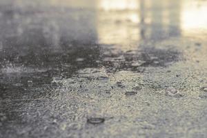 Rain drops in the water heavy on asphalt shade of black shadow and reflection of dark sky in the city. high contrast during autumn photo