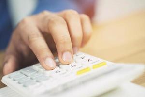 Close up businessman hand using calculator  and writing in a notebook counting making notes Accounting at doing finance at office.  Savings finances concept. note pad photo