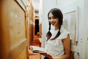 Girl with pigtails in white blouse at old library. photo