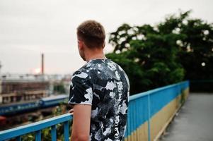 Lifestyle portrait of handsome man posing on the street of city and looking at train station. photo