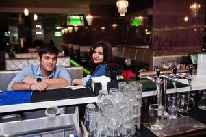 Stylish asian couple wear on jeans sitting on chair at bar in club. photo
