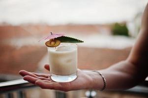 Alcoholic cocktail in glass on hand of barman. photo