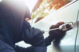 Close up car thief hand holding screwdriver tamper yank and glove black stealing automobile trying door handle to see if vehicle is unlocked  trying to break into inside. photo