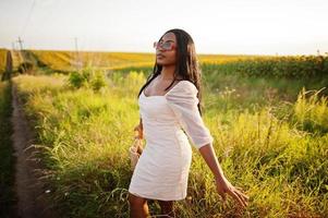 una mujer negra muy joven usa una pose de vestido de verano en un campo de girasoles. foto