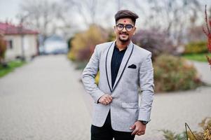 Stylish indian man with bindi on forehead and glasses, wear on suit posed outdoor. photo