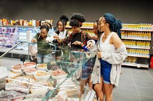 Group of five african womans buying meat dishes in supermarket. photo