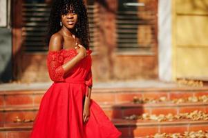 Stylish trendy afro france curly woman posed at autumn day in red dress. Black african female model. photo