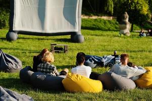 joven grupo multiétnico de personas viendo películas en poof en cine al aire libre. foto