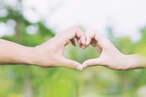 Young couple lover show holding hands make heart shape over in public parks. photo