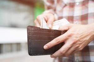 Businessman Person holding an wallet in the hands of an man take money out of pocket. photo