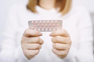 manos de mujer abriendo píldoras anticonceptivas en la mano. comiendo píldora anticonceptiva. la anticoncepción reduce el concepto de parto y embarazo. foto