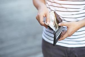 hipster hombre manos sosteniendo billetera con tarjetas de crédito y pila de dinero. foto