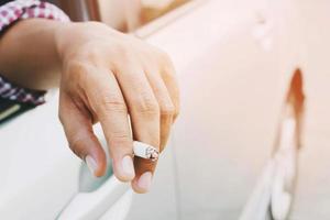 close up man hand hold smoking a cigarette in car while driving travel. photo