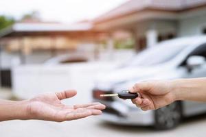 la llave del auto, el hombre que entrega le da la llave del auto al otro hombre en el auto como fondo de casa. deje espacio para escribir una descripción del texto del mensaje. foto