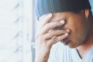 Young man close up portrait worried sad and hold the head with hand stressed standing show your emotions intense temper. symptom Depressed. photo
