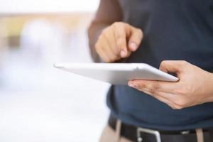 close up hand  Business man working using a digital tablet pc device while standing in front of in an office building overlooking the city. photo