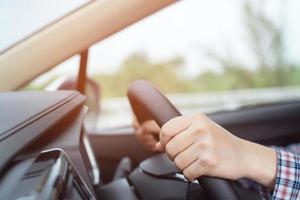 Close up of hand hold steering wheel young woman driving a car riding on the road. driver trip of travel. photo