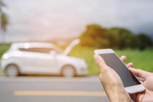 close up businessman hand using a mobile smart phone call a car mechanic ask for help assistance because car broken. photo