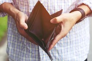 close up man person holding an empty wallet in the hands of an man no money out of pocket in front of the shop store. No money to pay shopping purchase Sell or Payment. photo