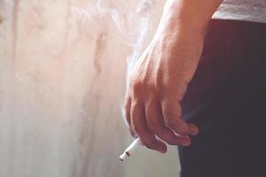 Image of cigarette in man hand with smoke. photo