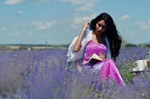 hermosa niña india usa vestido tradicional saree india sentada en un campo de lavanda púrpura con decoración. foto