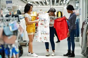 tres mujeres africanas eligiendo ropa en la tienda. dia de compras. foto