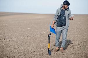 South asian agronomist farmer with shovel inspecting black soil. Agriculture production concept. photo