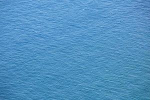 vista aérea de la superficie del mar azul con olas de un dron, vacío en blanco a fondo. enfoque suave. foto