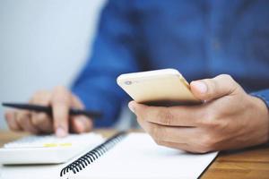 Close up businessman hand using calculator  and writing in a notebook counting making notes Accounting at doing finance at office.  Savings finances concept. note pad photo
