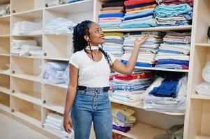 Cheerful african american woman stand near shelves with towels in the self-service laundry. photo